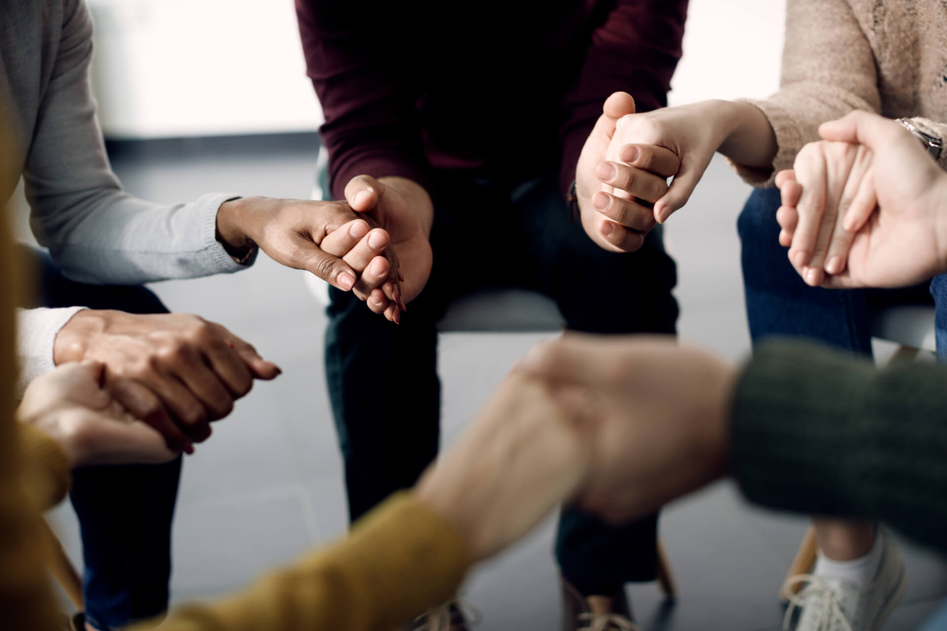 closeup-group-people-holding-hands-psychotherapy-session